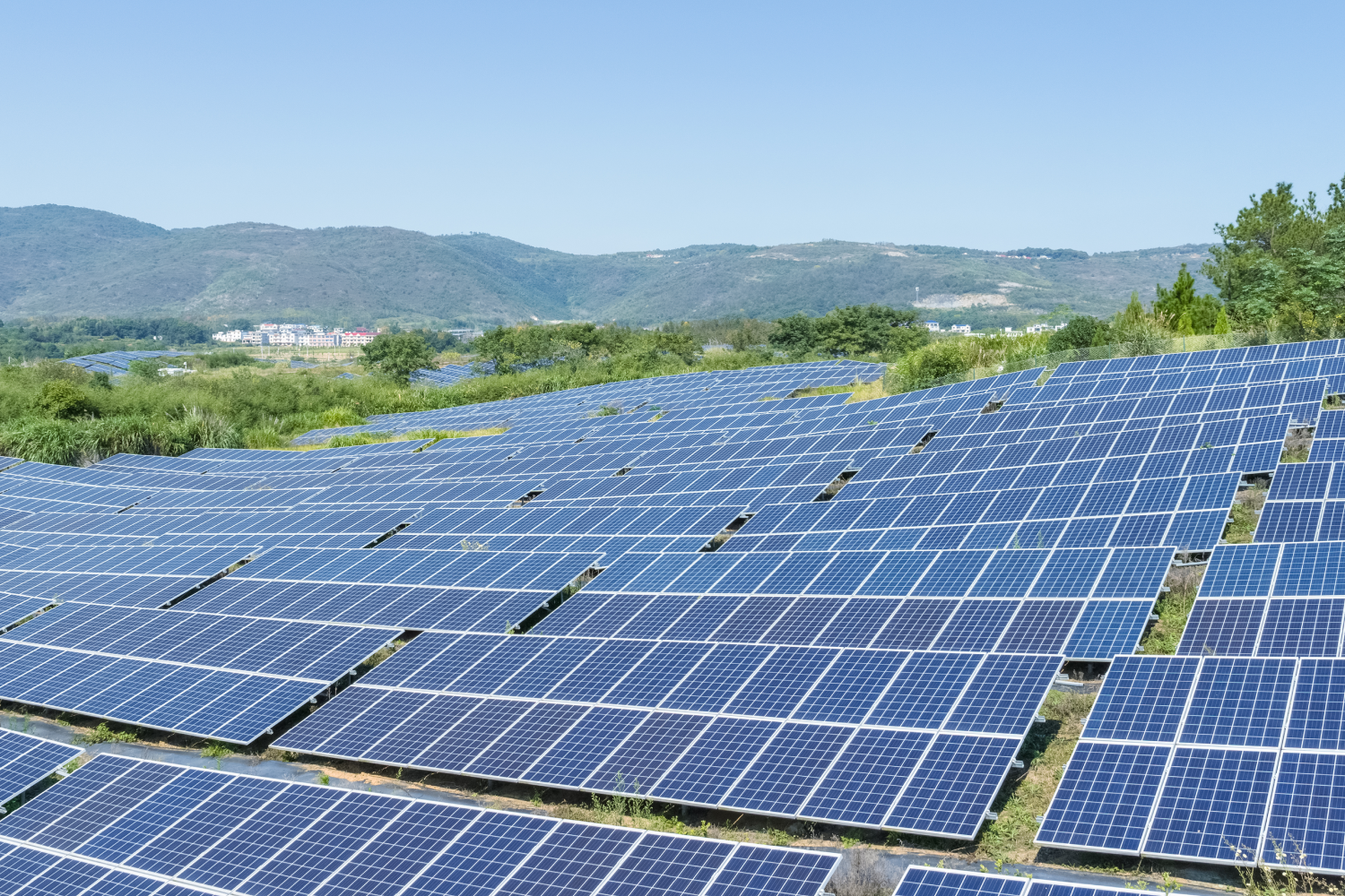 Photovoltaic energy Campo de paneles solares en un paisaje montañoso, con cielo despejado y vegetación circundante, destacando la energía renovable y la sostenibilidad.