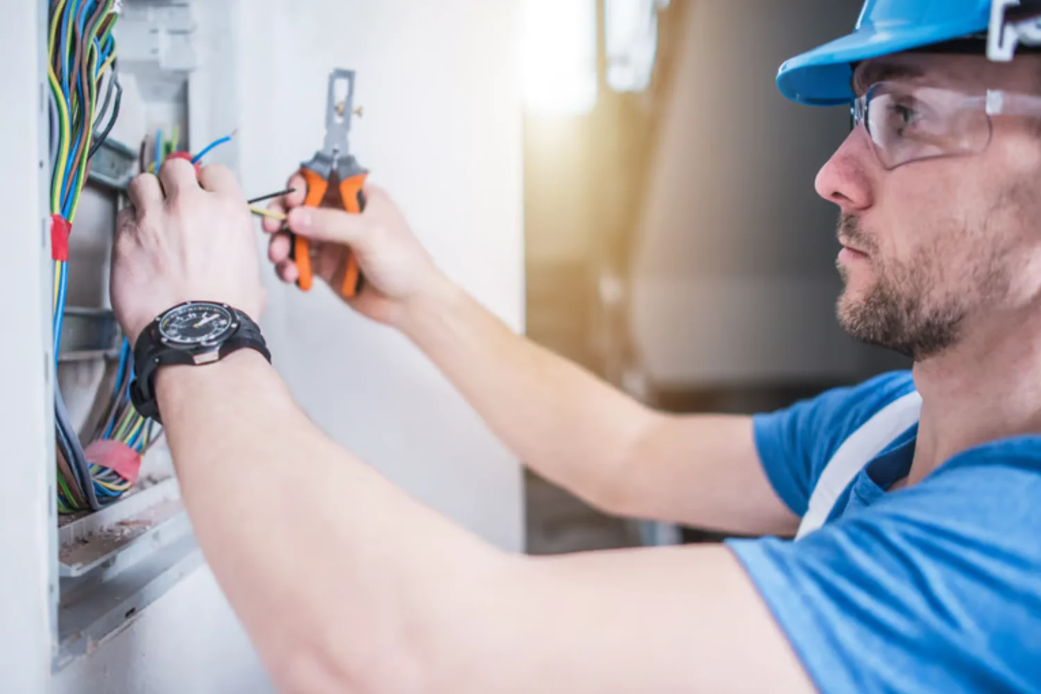 Técnico electricista trabajando en un panel eléctrico, utilizando herramientas para conectar cables. La imagen muestra un enfoque en la precisión y seguridad durante el proceso de instalación eléctrica.