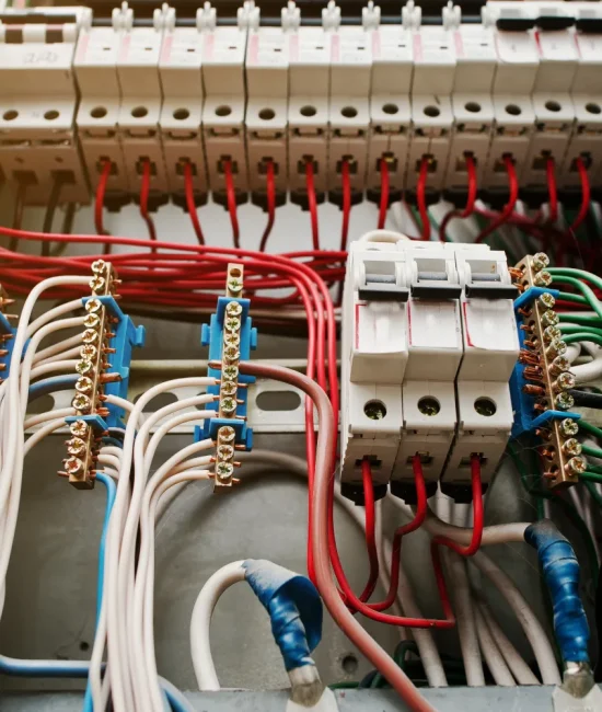 Panel eléctrico con múltiples interruptores y cables de diferentes colores, incluyendo rojo, blanco y verde, organizados en una instalación eléctrica.